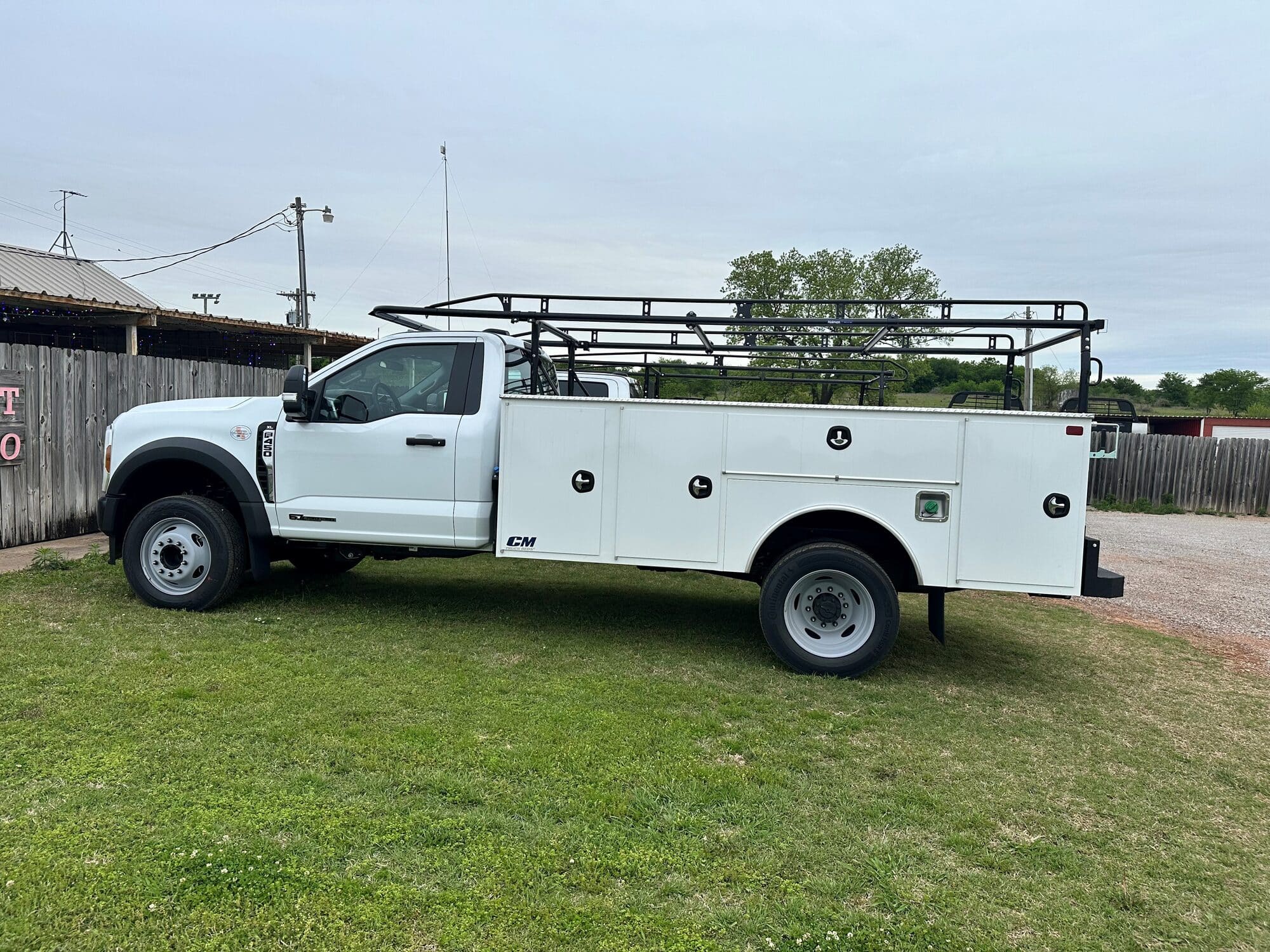 White Ford service-body truck with side storage compartments and an overhead material rack at DJ FleetWorX