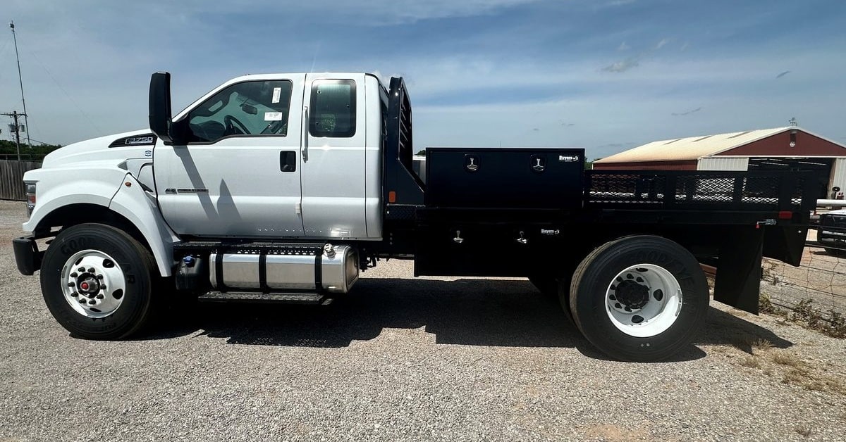 Ford F-750 with a black flatbed, side rails, and toolboxes outside the DJ FleetWorX shop