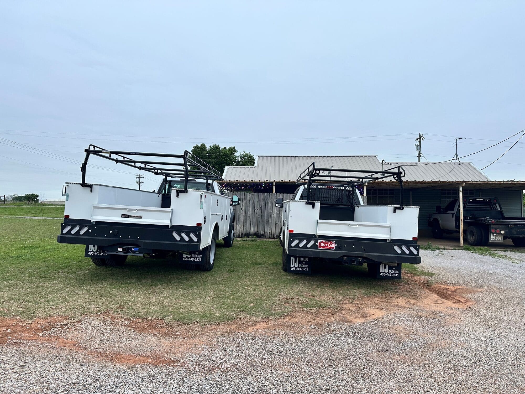 Two completed white service-body trucks with overhead material racks at DJ FleetWorX